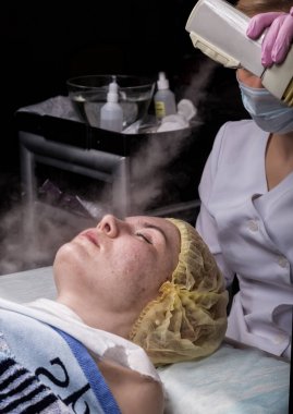 Doktor bir buhar ile kadın cilt temizler. güzellik te sorunlu genç kadın. Kozmetoloji kavramı