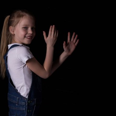 beautiful blonde little girl on a dark background. She stands in different poses and shows different emotions. free space for your text clipart