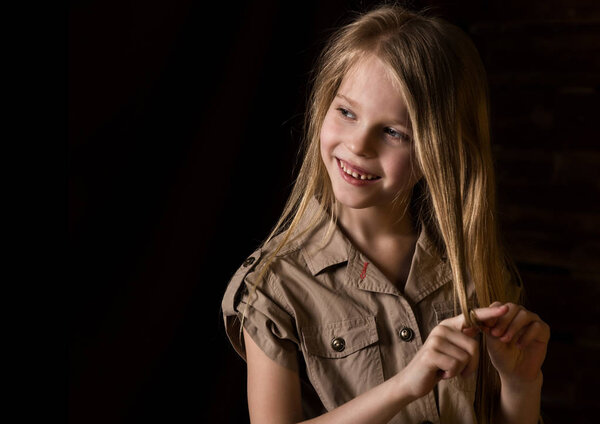 beautiful lovely little blonde girl with different emotions on a dark background