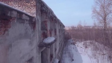 Terk edilmiş binanın üzerinden uçarken, eski bir kış mevsiminde yıkılan bina. Havadan görünüm 4k