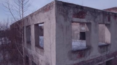 Terk edilmiş binanın üzerinden uçarken, eski bir kış mevsiminde yıkılan bina. Havadan görünüm 4k