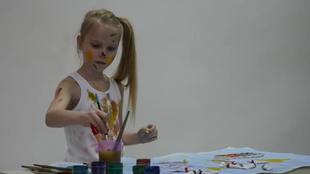 어린 여학생. 귀여운 소녀 화가가 테이블에 자신의 옷에 그립니다. 슬로우 모션 — 비디오