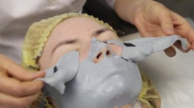 kozmetolojist spa salonunda kadın yüzü için çamur maskesi kaldırır. yüz gençleştirme prosedürü, spa tedavileri