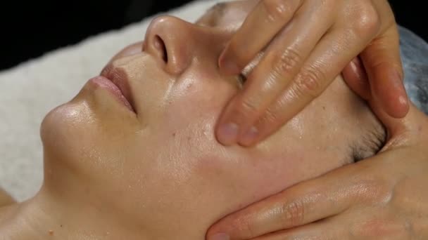 Пластиковий масаж обличчя в спа-сателіті. жінка користується послугами професійного масажиста. повільний рух — стокове відео