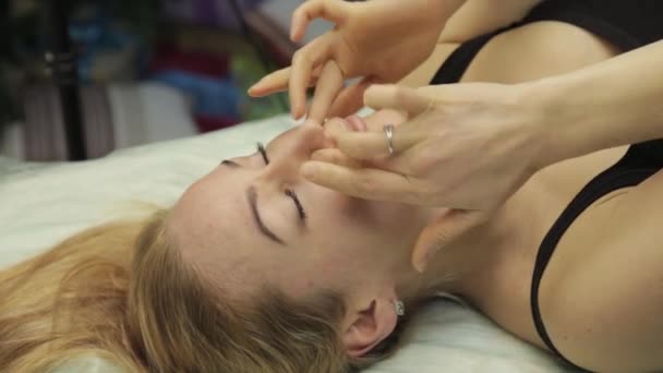 Blond kvinna gör själv-massage, ansiktsbehandling massage i sängen hemma. — Stockvideo