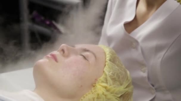 El médico limpia la piel de las mujeres con vapor. mujer joven con problemas de piel en la esteticista. Concepto de cosmetología — Vídeo de stock