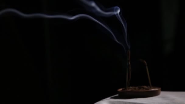 Bâtonnets d'encens qui brûlent, la fumée bleue coule lentement sur un fond sombre — Video