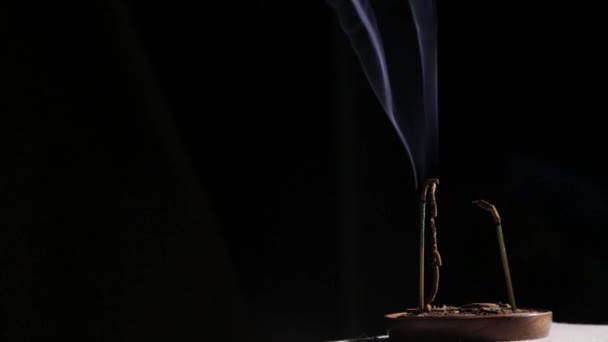 Incense sticks burning, blue smoke slowly flows on a dark background — Stock Video