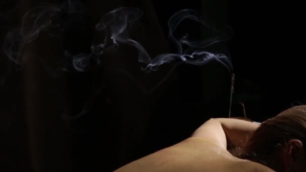 Массажист делает акупрессуру на женской спине. Ладан горит, голубой дым медленно течет. Альтернативная медицина Китая . — стоковое видео