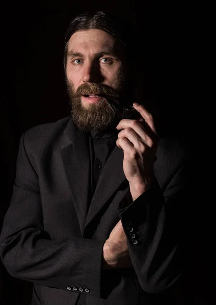 Vintage handsome bearded man with a smoking pipe on a dark background — стоковое фото