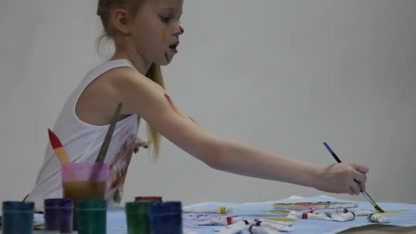 Mała uczennica. Cute Little Girl malarz rysuje na stole i na siebie na jej ubrania. Zwolnionym — Wideo stockowe