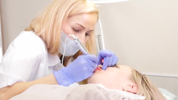 Doctor kosmetolog gör förfarandet för permanent makeup för kvinnliga klient läppar. 4K — Stockvideo