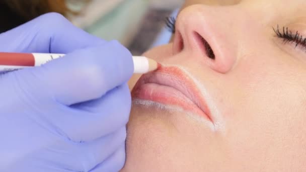 Schoonheidsspecialiste schetst de contour van de lippen. Permanente make-up voor rode lippen van mooie vrouw in schoonheidssalon. 4k — Stockvideo