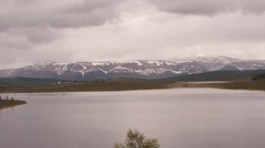 Bir su yüzeyine yansıyan fırtına bulutları ile dağ gölü timelapse görünümü