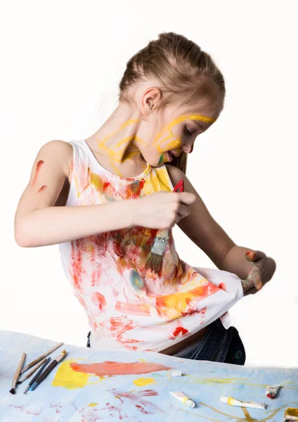 可爱的小女孩画家画在桌子上，自己在她的衣服上。慢动作 — 图库照片