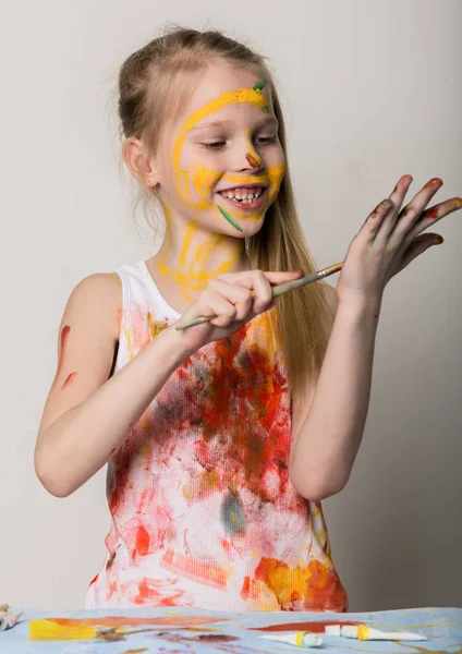 Nettes kleines Malmädchen zeichnet auf dem Tisch und auf sich selbst auf ihren Kleidern. Zeitlupe — Stockfoto