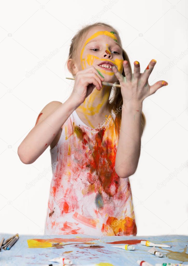 Little schoolgirl. Cute little girl painter draws on the table and on himself on her clothes. slow motion