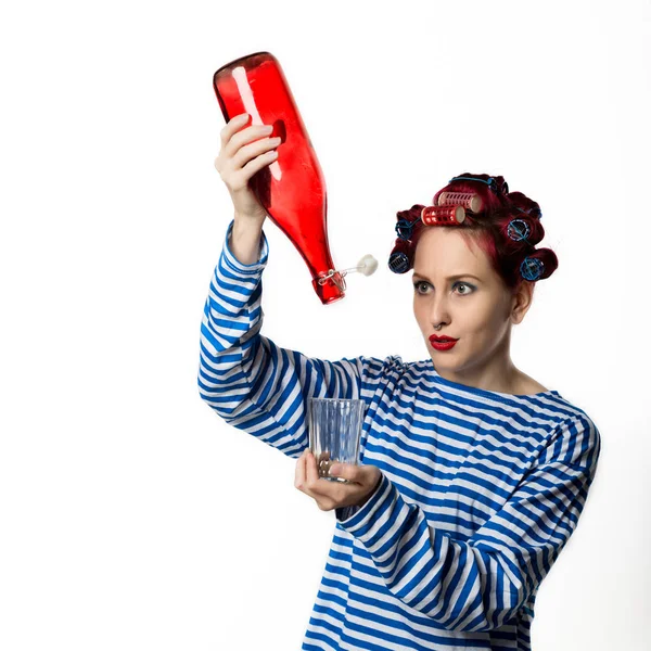 Extraña ama de casa sosteniendo una botella vacía de vino y vidrio sobre un fondo blanco. Concepto adicción al alcohol femenino — Foto de Stock