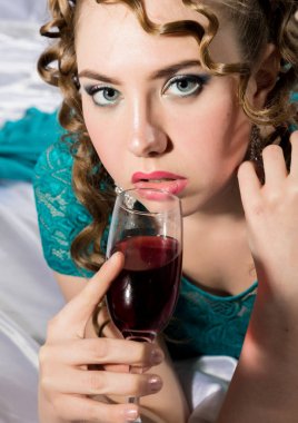 gizemli genç kıvırcık kadın yatakta istirahat ve kırmızı şarap içiyor