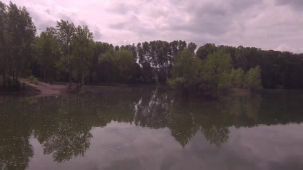 Vue aérienne. Vol bas au-dessus du lac au matin ensoleillé d'été. Arbres verts et collines, reflet des nuages à la surface du lac. 4K — Video