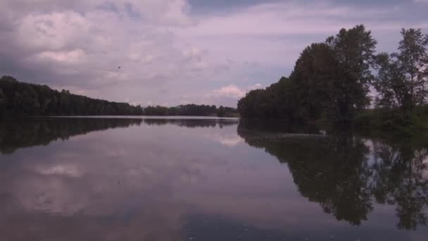 हवाई दृश्य। धूप गर्मियों की सुबह झील पर कम उड़ान। हरे पेड़ और पहाड़ियां, झील की सतह पर बादलों का प्रतिबिंब। 4K — स्टॉक वीडियो