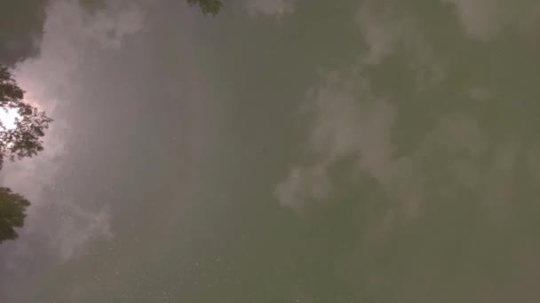 Низкий полет над поверхностью озера, отражение облаков в зеленоватой поверхности воды. 4K — стоковое видео