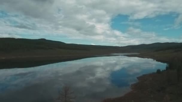 Vista aérea do lago de montanha com belas nuvens refletidas em uma superfície de água. floresta de coníferas na costa — Vídeo de Stock