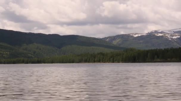 Utsikt över fjällsjö med storm moln reflekteras i en vattenyta. barrskog på stranden — Stockvideo