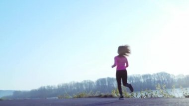 gün doğumu veya gün batımı sırasında nehir kıyısında koşu sportif kız. atletik kadın sağlıklı yaşam tarzı kavramı spor için gider. yavaş çekim