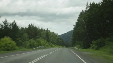 bir bulutlu bahar sabahı araba sürücü sırasında ön cam ile Dağlık görünümü. Highland altay pitoresk kır yolları