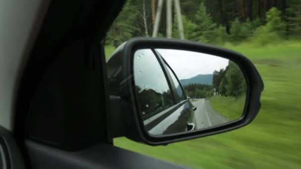 Blick auf den Rückspiegel, Spiegelung einer Bergstraße durch die Landschaft an einem Sommertag — Stockvideo