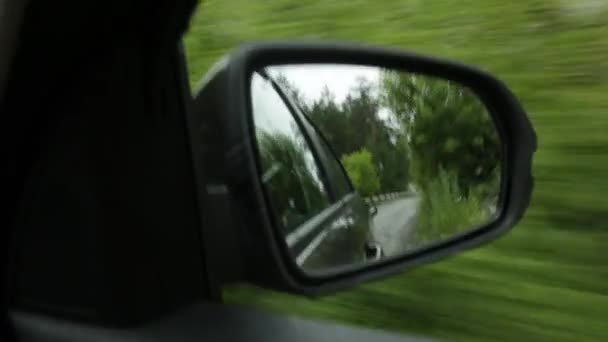 Vista del espejo lateral, reflejo de un camino de montaña a través del campo en un día de verano — Vídeo de stock