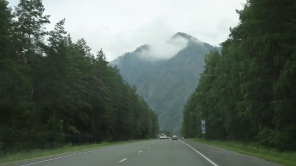 Vista de las tierras altas a través del parabrisas durante el viaje en coche en una mañana nublada de primavera. Pintorescas carreteras rurales de Highland Altay — Vídeos de Stock