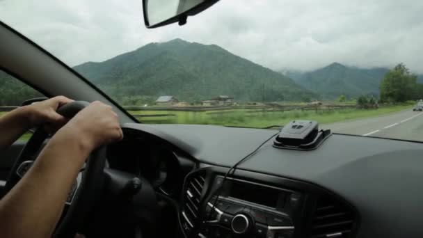 Pemandangan dataran tinggi melalui kaca depan. dashboard dan roda kemudi dengan tangan pengemudi, kabut pagi di pegunungan — Stok Video