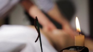 Tütsü çubukları ve mum yakma, mavi duman yavaş yavaş akar. spa salonunda sırt masajı. masaj terapisti bir kadın vücut klasik bir masaj yok