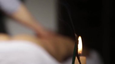 Tütsü çubukları ve mum yakma, mavi duman yavaş yavaş akar. spa salonunda sırt masajı. masaj terapisti bir kadın vücut klasik bir masaj yok