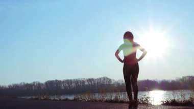 atletik kadın gün doğumunda nehir kıyısında spor için gider. yavaş çekim