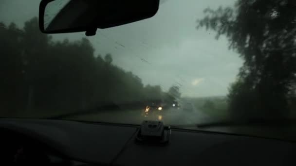 Jazda w nieprzyjemny deszczowy dzień, widok na drodze wiejskiej przez przednią szybę podczas jazdy samochodem. Krople deszczu na szybę przednią szyby samochodu — Wideo stockowe
