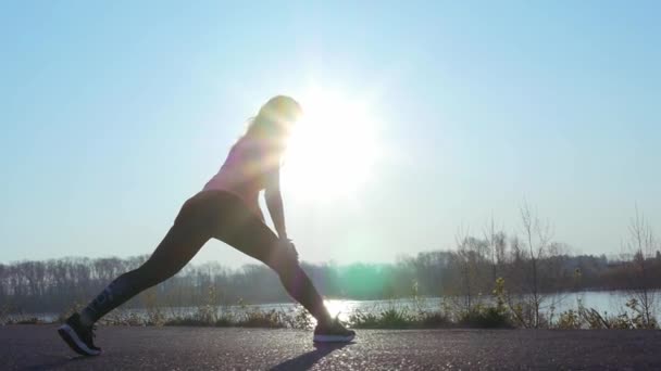 Atletische vrouw gaat in voor sport op de oever van de rivier bij zonsopgang. Slow Motion — Stockvideo