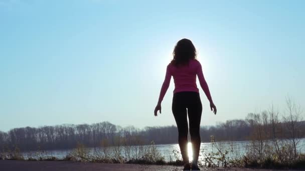 Donna atletica entra per lo sport sulla riva del fiume all'alba. rallentatore — Video Stock