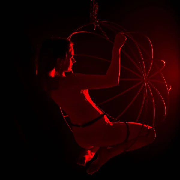 Σιλουέτα της σέξι θηλυκιά χορεύτρια με κόκκινο φως σε σκούρο φόντο. γυναίκα σε ένα κορμάκι με μεταλλικά δαχτυλίδια. νυχτερινό κέντρο — Φωτογραφία Αρχείου