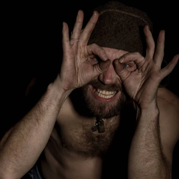 Странный русский мужчина с обнаженным туловищем и шерстяной шляпой, делающий разные знаки руками — стоковое фото