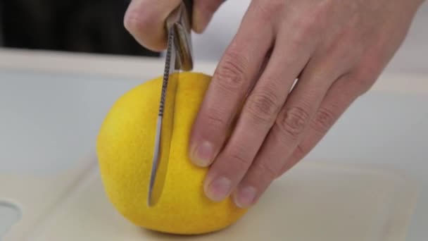 Confiseur à l'aide d'un couteau coupé une oranges. deux moitiés d'orange sur une planche à découper — Video