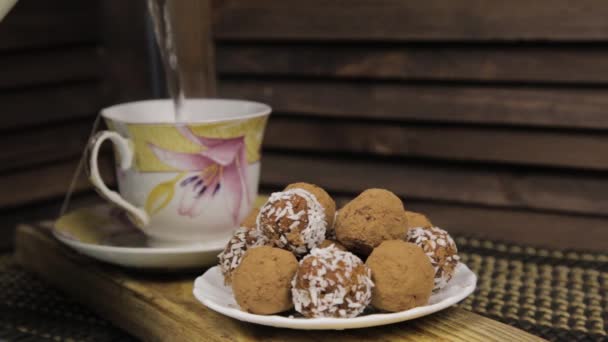 Chocolate candies and tea set on a wooden table. Porcelain tea set on a woodan background — Stock Video