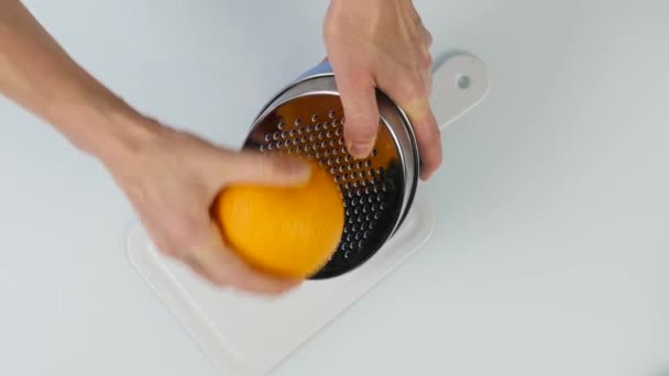 Confeiteiro corta a casca de laranja, citrus zester ralar casca de laranja descascamento. Vista superior de 4K — Vídeo de Stock