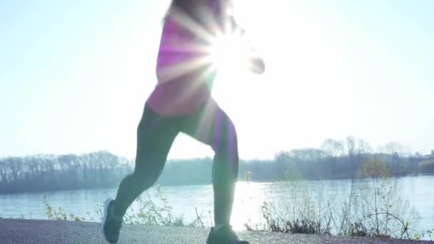 Ragazza sportiva che fa jogging lungo la riva del fiume durante l'alba o il tramonto. sano concetto di stile di vita della donna atletica va in per lo sport. rallentatore — Video Stock