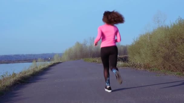 Gün doğumu veya gün batımı sırasında nehir kıyısında koşu sportif kız. atletik kadın sağlıklı yaşam tarzı kavramı spor için gider. yavaş çekim — Stok video