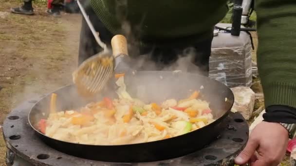 Μαγειρεύοντας λαχανικά με κρέας σε εξωτερικούς χώρους. τηγανητά λαχανικά σε ένα καζάνι. διακοπές. καπνός ανεβαίνει αργά πάνω από το τηγάνι. αργή κίνηση. — Αρχείο Βίντεο