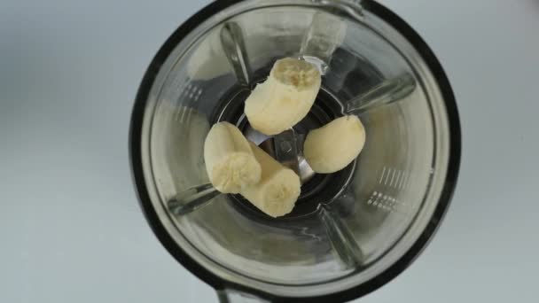 Mujer joven cocinando un cóctel de frutas y bayas en una licuadora. alimentación saludable, cocina, comida vegetariana, concepto de dieta. vista superior 4K — Vídeo de stock