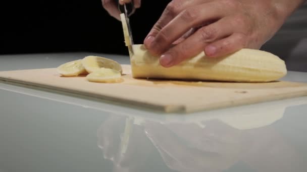 A nők segítségével konyhai kés slide vágott banán a fa vágódeszka. Banán szeletelés szárított gyümölcsökhöz — Stock videók